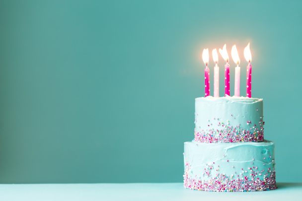 Tiered birthday cake with pink candles and sprinkles - Zdjęcie, obraz