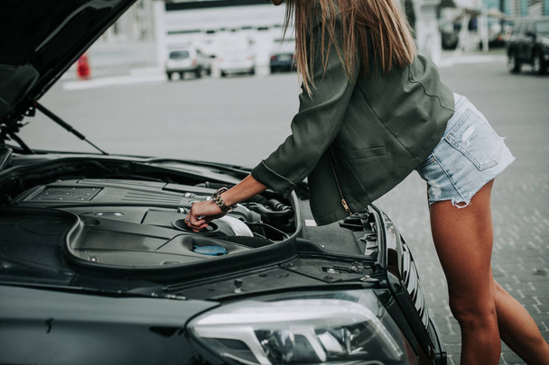 Pretty woman looking at engine for car - Foto, Bild