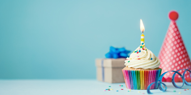 Verjaardagsfeestje achtergrond met cupcake, feestmuts en aanwezig - Foto, afbeelding