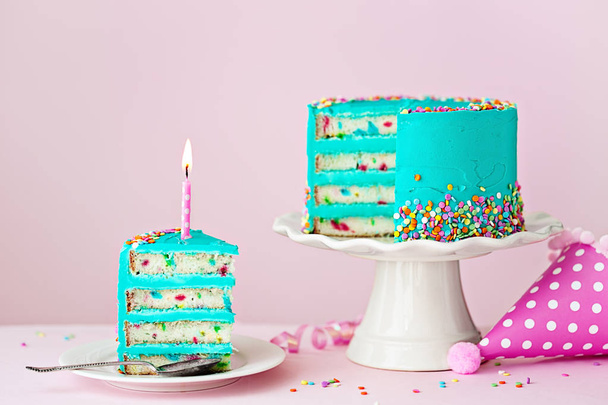 Bolo de aniversário colorido com uma fatia e uma vela
 - Foto, Imagem