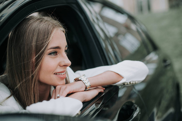 Cheerful female leaning on door of automobile - Foto, afbeelding