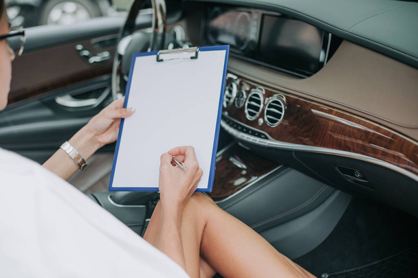 Focused employer writing on paper in car - Фото, зображення