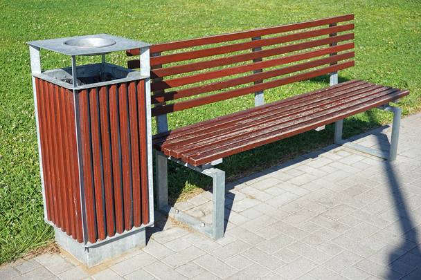 Мусорный бак и деревянная скамейка в парке
 - Фото, изображение