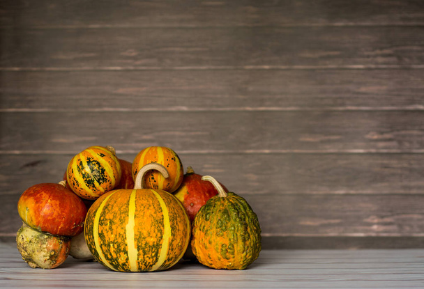 Big and mini pumpkins stacked to left on wooden background, copy space - Fotografie, Obrázek