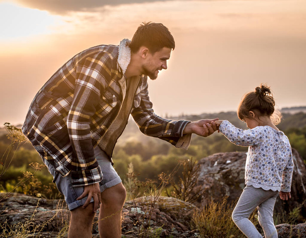 папа и дочь гуляют на природе на закате концепция семейные ценности, семейные отношения
 - Фото, изображение