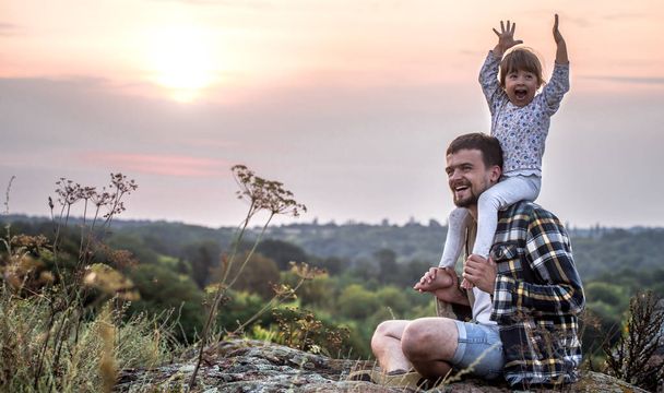 Joyeux famille aimante, papa garde sa petite fille sur ses épaules au coucher du soleil, le concept de relations familiales et d'amitié
 - Photo, image