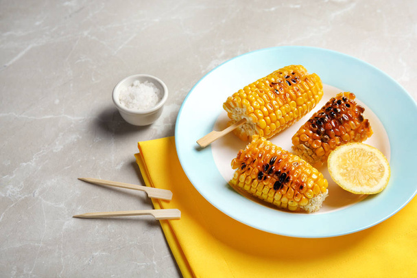 Plate with delicious grilled corn cobs on light table - Fotografie, Obrázek