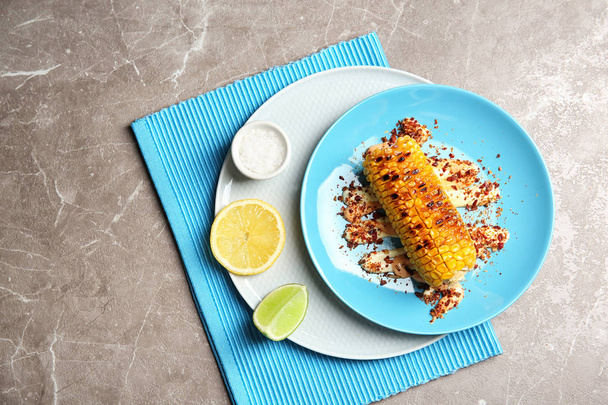 Plate with delicious grilled corn cob and spices on table, top view - Фото, зображення