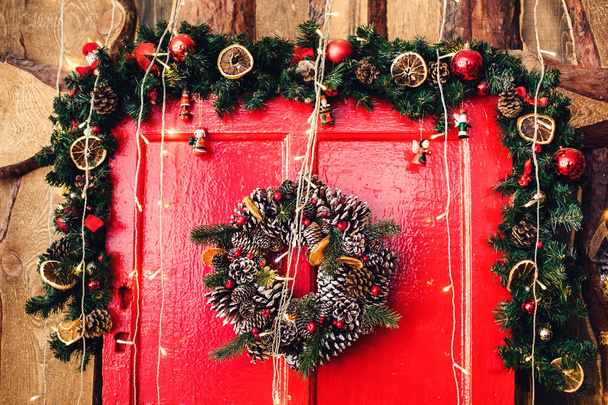Θραύσμα από κόκκινη ξύλινη πόρτα με Χριστουγεννιάτικη διακόσμηση. - Φωτογραφία, εικόνα
