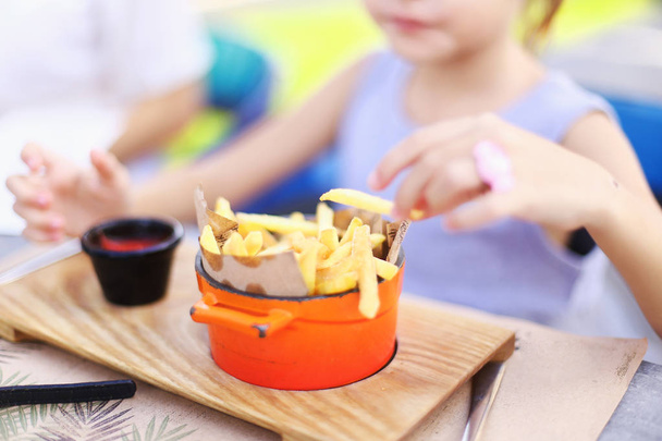 Kid eating fried potato, focus on French fries. - Foto, Imagem