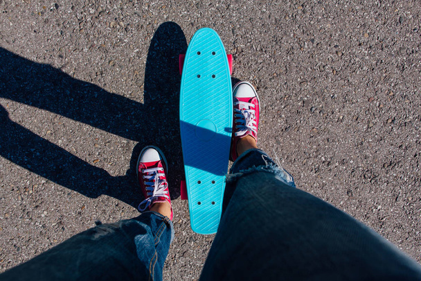 Close up feet of a girl in red sneakers and blue penny skate board with pink wheels. Urban scene, city life. Sport, fitness lifestyle. - Фото, изображение