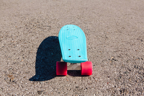 Plástico azul monopatín penny board con ruedas de color rosa se levanta en la pista
. - Foto, Imagen