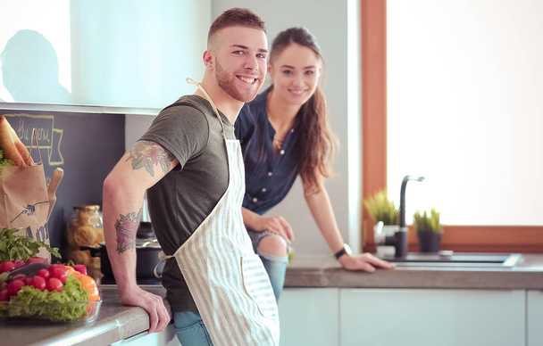 Beautiful young couple is having fun in kitchen at home - 写真・画像