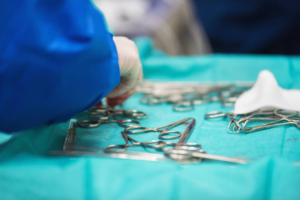 Chirurg hebt ein Instrument aus dem Tablett mit chirurgischen Instrumenten - Foto, Bild