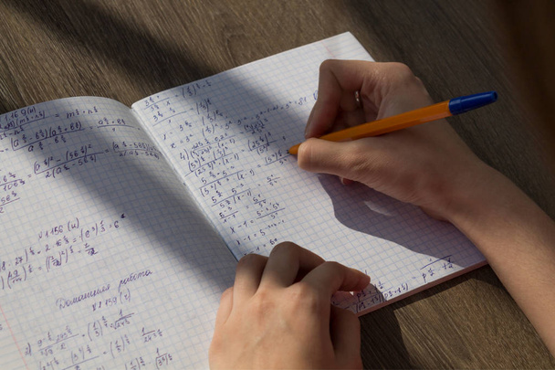 Жіноча рука пише математичні формули в блокноті. Шкільне домашнє завдання в математиці
 - Фото, зображення