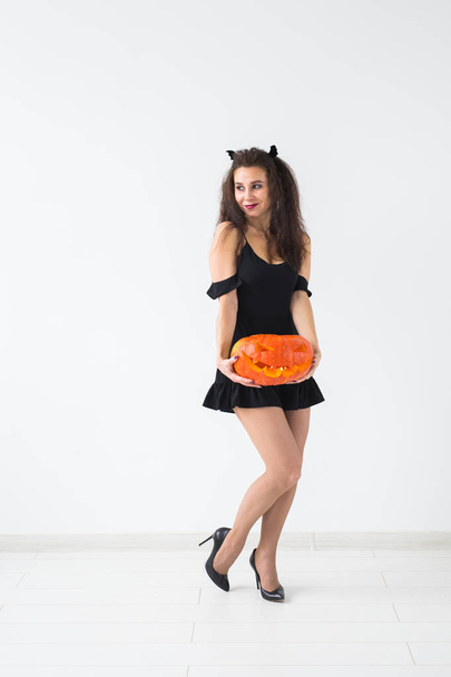 Cute gothic woman in halloween style clothes with pumpkin in hands - Foto, Bild