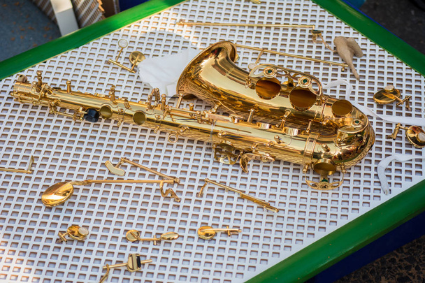 Gedemonteerde saxofoon en diverse schroevendraaiers close-up - Foto, afbeelding