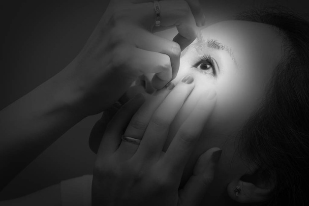 アジアの若い女性は、目の治療のため点眼薬を使用します。赤み、目の乾燥、アレルギー、目のかゆみ - 写真・画像