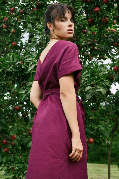 Divat klasszikus ruhában pózol egy apple fák között gyönyörű barna nő portréja - Fotó, kép