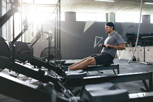 Functional Training. Man Doing Exercise On Rowing Machine At Gym - Foto, Imagen