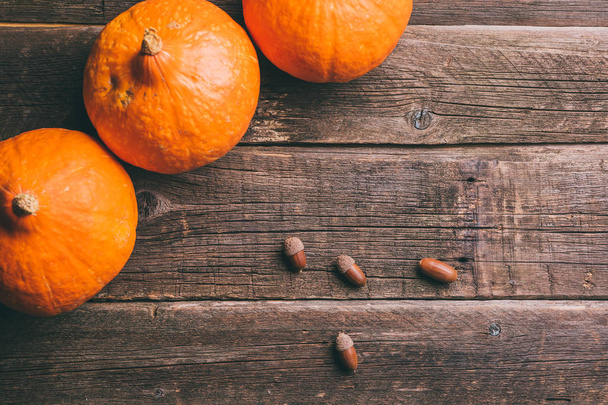 Three orange pumpkins and acorns on old wooden background with copy space, autumn harvest, Halloween or Thanksgiving concept - 写真・画像