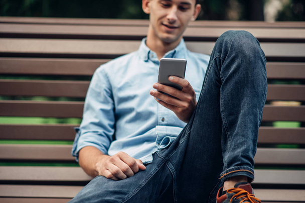 Телефонная зависимость, наркоман с помощью смартфона на скамейке запасных в парке, социально зависимые люди
 - Фото, изображение