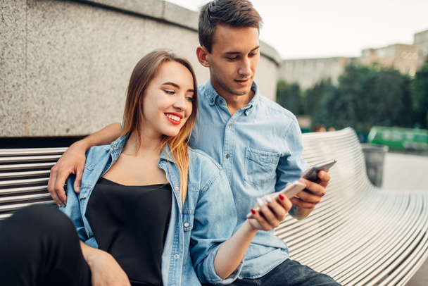 Phone addiction, portrait of addict couple using smartphones on the bench in park, social addicted people - Φωτογραφία, εικόνα
