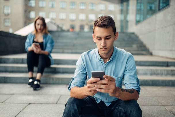 Phone addiction, man and woman using gadgets, social addicted people, modern lifestyle - Фото, зображення