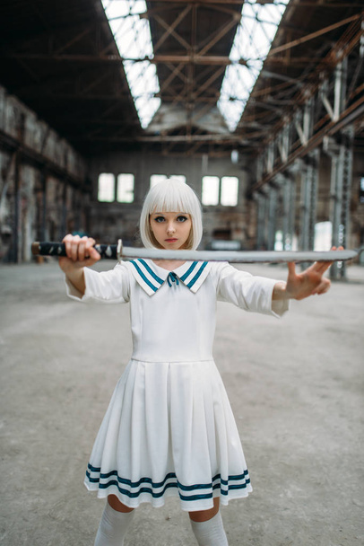 Pretty anime style blonde woman with sword. Cosplay fashion, asian culture, doll with blade on abandoned factory, cute woman with makeup - Photo, image