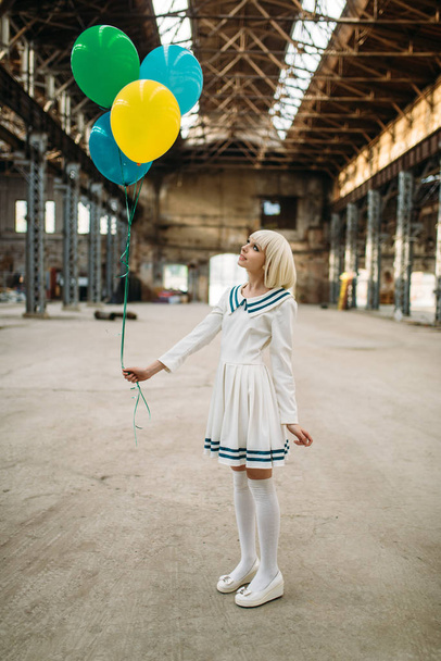 hübsche blonde Dame im Anime-Stil mit bunten Luftballons. Cosplay-Mode, asiatische Kultur, Puppe im Kleid, niedliche Frau mit Make-up im Factory Shop - Foto, Bild