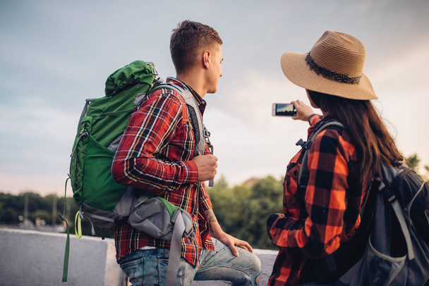 Туристы с рюкзаками делают селфи на экскурсии по туристическому городу. Летние походы. Путешествие молодого человека и женщины
 - Фото, изображение