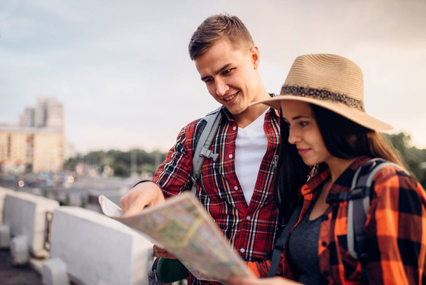 Wanderer mit Rucksäcken sieht auf der Karte, Ausflug in die Touristenstadt. Sommerwandern. Wanderabenteuer junger Mann und Frau - Foto, Bild
