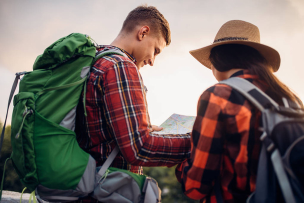ハイカーのバックパックとは、マップ、観光の町で遠足に見えます。夏のハイキング。若い男と女の冒険をハイキングします。 - 写真・画像