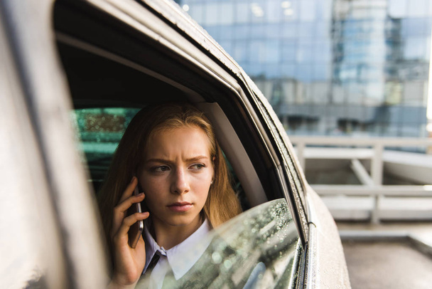 Portrait of frown girl in car with mobile - Foto, immagini