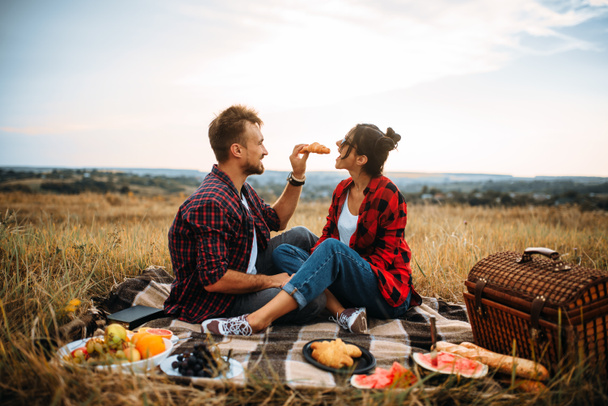 Happy love couple on picnic in summer field. Romantic junket of man and woman - Photo, Image