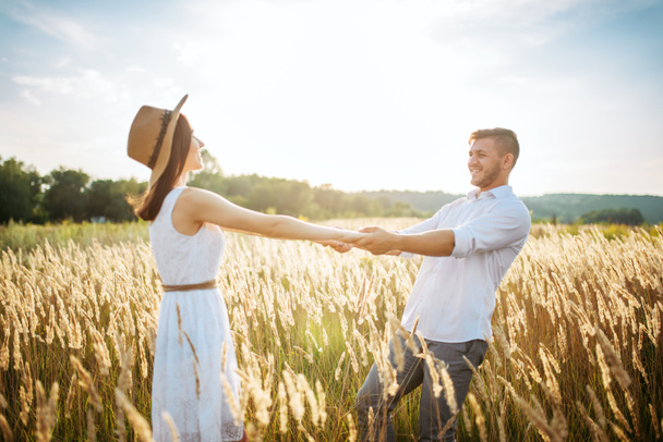 Szerelmes pár kéz a kézben, sétál a rozs mező. Aranyos család nyári réten - Fotó, kép