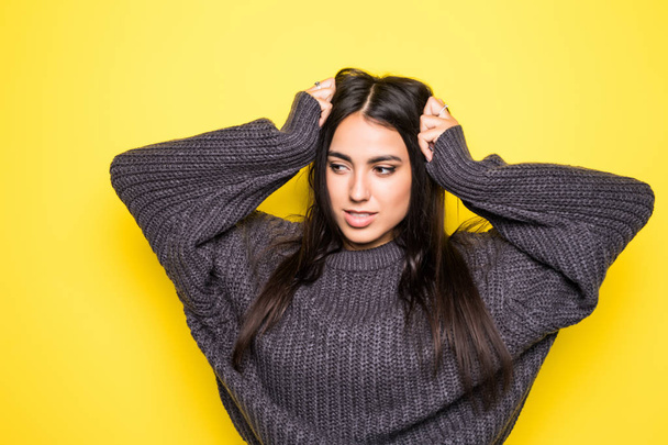 Beautiful woman sweater smiling, and looking at camera on yellow background. - Foto, Imagen