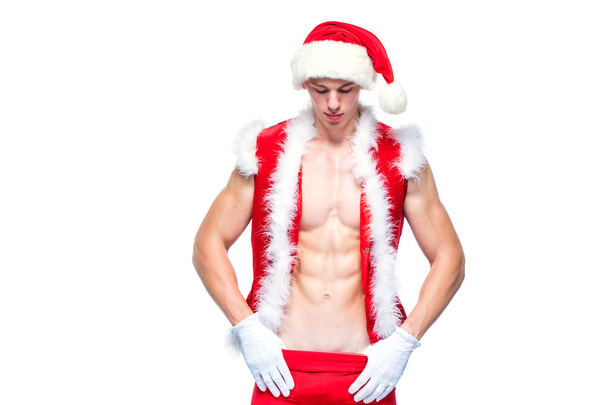 Sexy Santa Claus. Un joven musculoso con sombrero de Santa Claus demuestra sus músculos. Aislado sobre fondo blanco. - Foto, Imagen