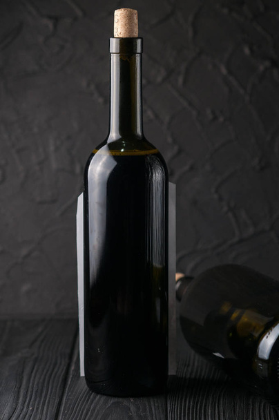Garrafas de vinho sobre fundo de madeira preta com uvas e queijo Camemberg
. - Foto, Imagem