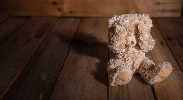 Konzept für Kindesmissbrauch. Teddybär bedeckt Augen, dunkler, leerer Hintergrund, Kopierraum - Foto, Bild