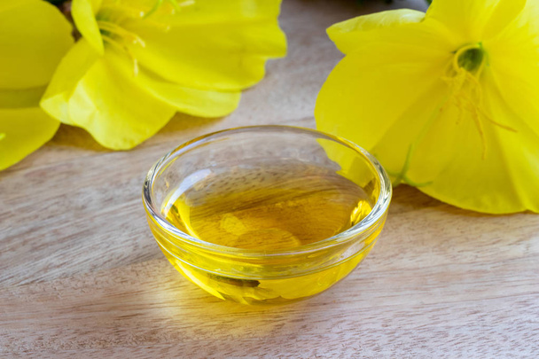 Evening primrose oil with blooming oenothera biennis plant  - Photo, Image
