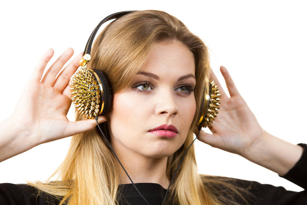 Relaxed young grunge woman wearing black and listening to music on headphones with spikes - Photo, image