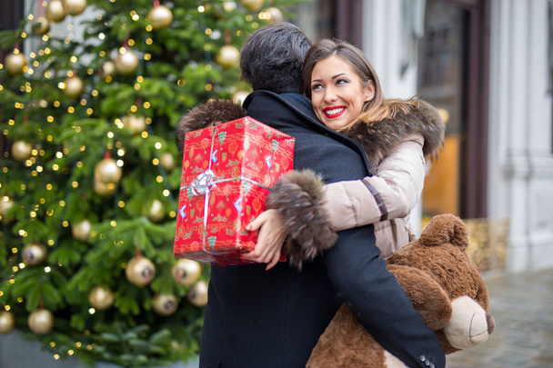 Feliz hermosa pareja joven abrazando e intercambiando regalos para Navidad durante el día
 - Foto, imagen
