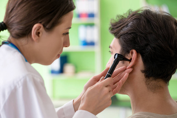 Tıbbi muayene sırasında kadın doktor hastaların kulaklarını kontrol ediyor.  - Fotoğraf, Görsel