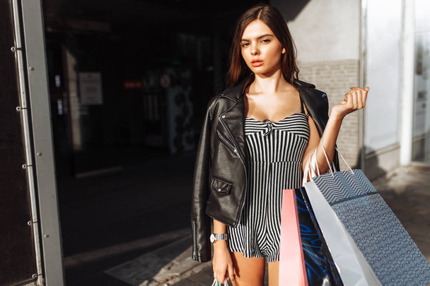 Beautiful stylish girl walking down the street, after shopping, holding bags, outdoors - Fotoğraf, Görsel