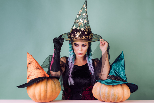 黒い帽子でハロウィンの魔女。女性がかぼちゃのポーズします。カボチャ頭のジャック ランタン。お菓子をくれないといたずらするよ。魔女の衣装でグラマー ファッションのセクシーな吸血鬼の女性. - 写真・画像
