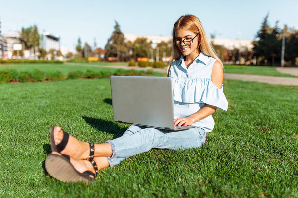 Счастливая красивая студентка, молодая женщина, работающая на ноутбуке в Парке, сидящая на лавке
 - Фото, изображение