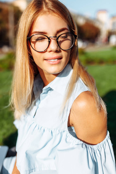 Portrait d'une belle fille émotionnelle avec des lunettes, une étudiante dans le parc, posant de bonne humeur
 - Photo, image