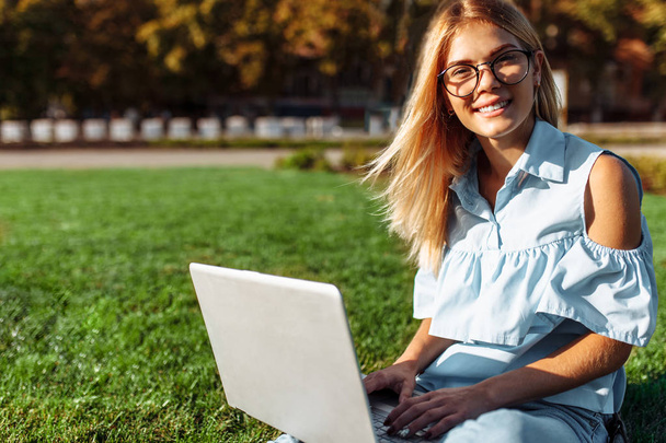 Happy handsome student, young woman working on laptop in Park sitting on lawn - Foto, afbeelding