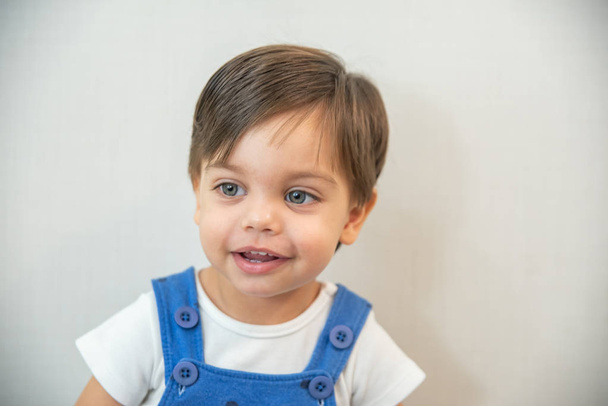 Bébé garçon mignon tout-petit - avec barboteuse bleue sur fond blanc - Sourire
 - Photo, image